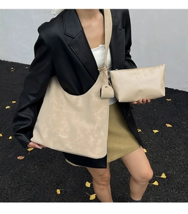 Detail view of large cream hobo tote with matching small pouch on autumn street