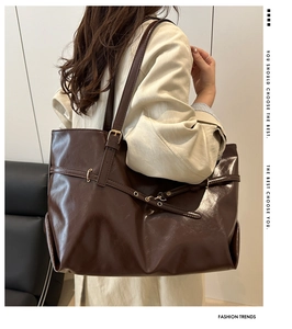 Detailed view of the dark brown leather tote bag with gold buckle and adjustable strap