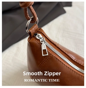 Detail of a brown leather bag showing a smooth silver metal zipper and precise stitching
