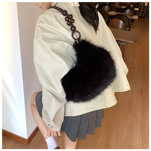 Detail of black heart-shaped faux fur bag with retro brown wooden bead strap