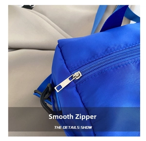 Close-up of smooth silver zipper on a bright royal blue nylon crossbody bag details