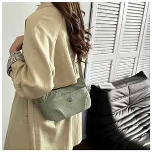 Detail of light green nylon shoulder bag with circular metal logo and side pocket