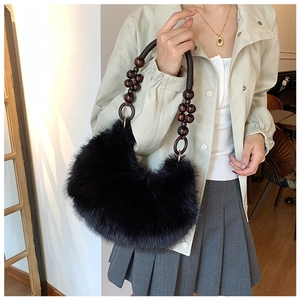 Detailed shot of black faux fur dumpling bag featuring wooden bead handle and metal rings