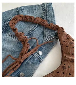 Détail d'un sac à main en velours côtelé marron avec motif cœur et nœud