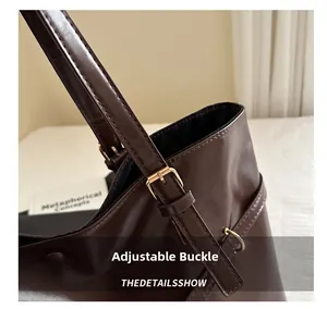 Close-up of a brown tote bag showing adjustable strap with a gold metal buckle detail