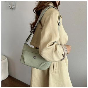 Detailed side view of sage green nylon crossbody bag with adjustable strap on a model
