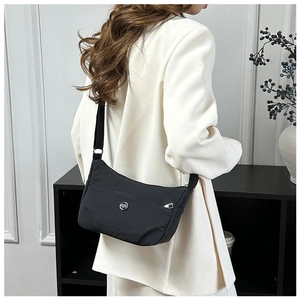Black crescent nylon crossbody bag worn by model in a minimalist interior setting