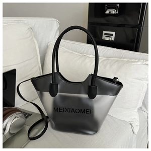 Gros plan du sac cabas gris translucide avec lettrage noir MEIXIAOMEI sur un canapé blanc