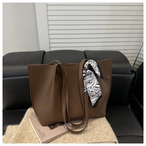 Detailed view of brown leather tote bag with stylish marble scarf on a cozy sofa