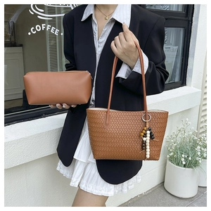 Detailed view of brown woven tote bag set with beaded charm and matching pouch