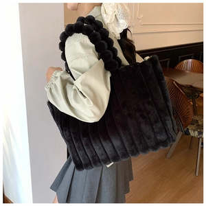 Détail du sac cabas en peluche noire avec texture rayée et bandoulière à pompons