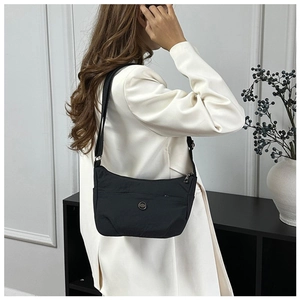 Close-up of black nylon crossbody bag worn over a white suit for a sleek contrast