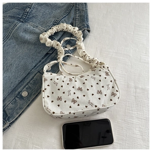 Detail of white corduroy heart print crescent bag with smartphone for size reference