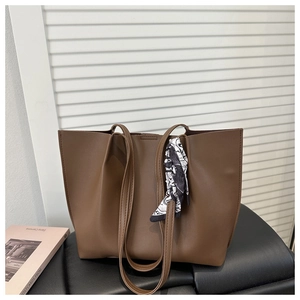 Detail of dark brown faux leather tote bag with elegant silk scarf on a sleek countertop