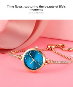 Makroaufnahme einer roségoldenen Armreif-Uhr mit blauem Zifferblatt und Kristall-Indizes
