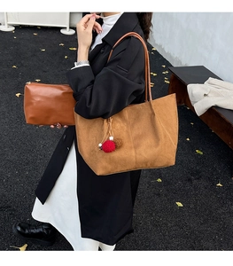 Close-up of brown suede tote bag and matching clutch with plush charm accessory