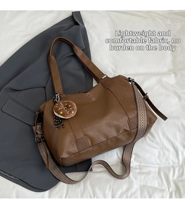 Detail of dark brown tote bag featuring lychee texture and woven shoulder strap