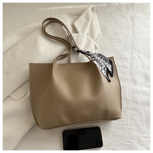 Detailed side view of beige leather tote bag with silk scarf and phone for scale