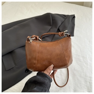 Detailed view of caramel leather shoulder bag with silver hardware and knotted handle design