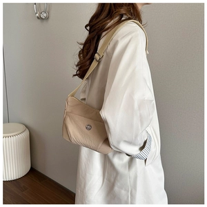 Detail of light beige nylon crossbody bag featuring a wide strap and metal logo