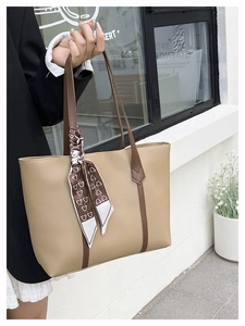 Close-up of khaki leather tote bag with brown straps and elegant floral printed scarf detail