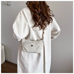 Detail view of the creamy white wrinkled leather texture and metal buckle on the crossbody bag