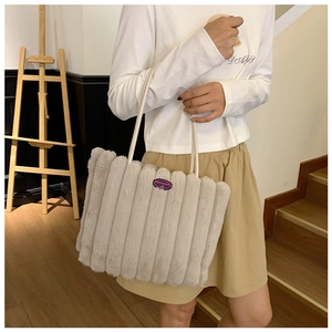 Close-up of beige plush tote bag with vertical stripes and cherry logo embroidery