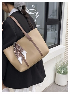Detail of large beige tote bag with brown trim and heart pattern scarf on shoulder