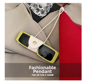 Macro detail of avocado green sunglasses in cream leather protective case with gold button