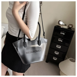 Détail d'un sac seau gris translucide avec poignée en cuir noir dans un décor moderne
