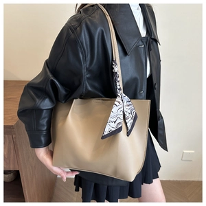 Detail of khaki leather tote bag featuring a decorative black and white patterned silk scarf