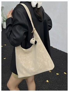 Detail of matte cream tote bag showing soft texture and shoulder strap on model