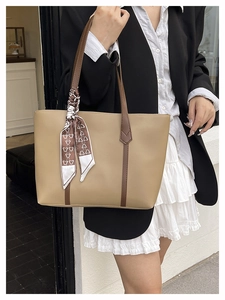 Close-up of a large khaki tote bag with brown handles and a decorative printed silk scarf