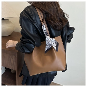 Detail of a large brown tote bag with a marble pattern silk scarf on the shoulder strap