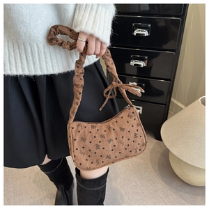 Detail of brown corduroy baguette bag with black bow and heart patterns with ruffled handle