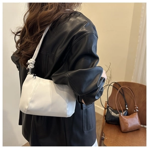 Detail of white leather shoulder bag featuring unique strap knot design and soft texture