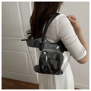 Close-up of clear PVC tote bag featuring black leather handles and inner zip pouch