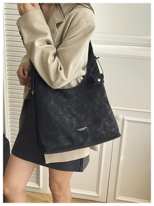 Detail of a large black tote bag with textured finish and matching side pouch charm