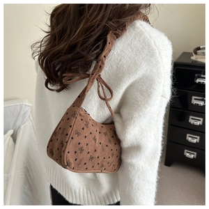 Close-up of brown corduroy underarm bag featuring black heart and bow prints