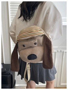 Detail of cute puppy backpack in brown corduroy fabric worn by a model in soft lighting