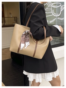 Detail of beige tote bag with brown straps and silk scarf tied to handle in street style