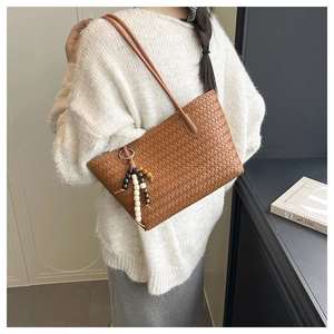 Brown hand-woven shoulder bag with beaded tassel detail on a fashion model