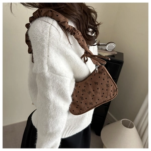 Close-up of brown corduroy bag with heart patterns and ruffled shoulder strap detail