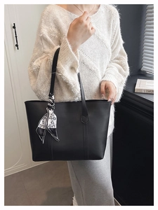 Shoulder view of a black leather tote bag with decorative heart pattern scarf detail