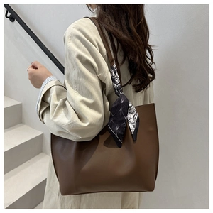 Detail of deep brown leather tote bag with stylish black and white patterned scarf