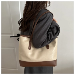 Detail of minimalist two-tone tote bag with brown straps and cream leather texture