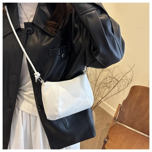 Close-up of white minimalist crossbody bag with refined leather texture and fine stitching