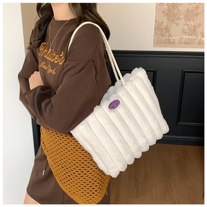 Detail of white plush tote bag with quilted texture and purple logo patch on faux fur
