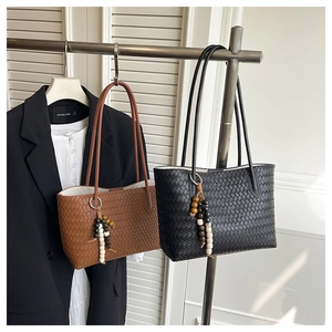 Detail of woven tote bags in brown and black with stylish wooden bead tassels and straps