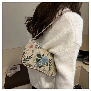Detail of floral tapestry underarm bag featuring a metallic silver bow charm
